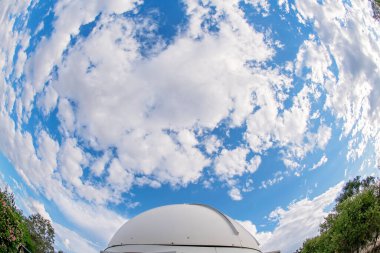Yuvarlak bir gözlemevi bulutlu, balık gözlü mercekle fotoğraflanmış.