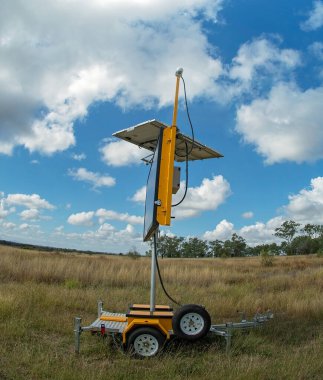 Clermont, Queensland, Avustralya - Mayıs 2021: Gezici güneş enerjili trafik ışıkları yol kenarında çimlerin üzerinde duruyor, balık gözü lensleri