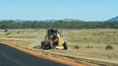 Clermont, Queensland, Avustralya - Mayıs 2021: Kesilmiş ağaçların olduğu bir alanda traktör yol kenarını derecelendiriyor