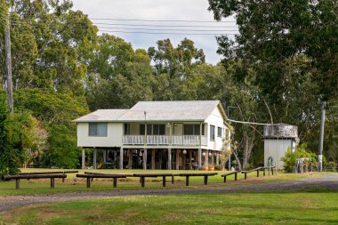 Mackay, Queensland, Avustralya - Mayıs 2021: Okyanus kıyısındaki bir banliyöde beton su tankıyla dolu eski bir plaj evi