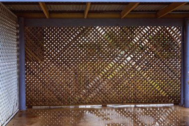 An old timber lattice carport that has just been washed out, wet water reflections on the concrete clipart
