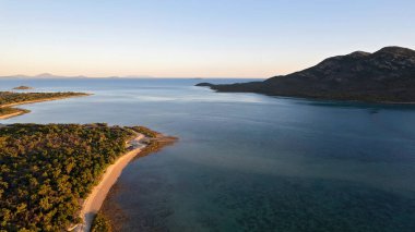 Çalı plajları ve sığ okyanusları kaplayan hava, güneşin doğuşuyla birlikte manzaraya sıcak bir ışık yayıyor.