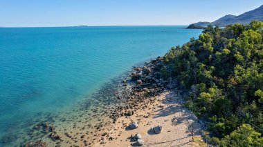 Gözlerden uzak, kumlu bir sahil alçak gelgit ve kristal berrak suyla kaplanmış kayalarla deniz tabanına doğru akıyor.