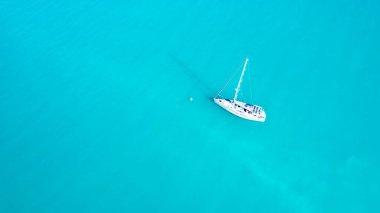 Mercan Denizi 'nin turkuaz okyanusunda tek başına demirli beyaz bir yatın üzerindeki hava manzarası.