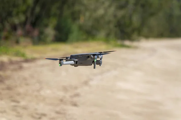 A drone flying on the beach hovering above the sand ready for takeoff