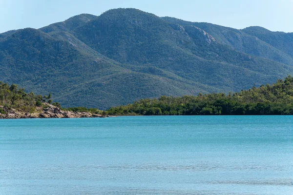 Calm Blue Ocean Rock Tree Lined Shore Forested Mountain Background — Foto Stock