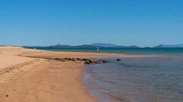 澳大利亚昆士兰州格洛斯特角 2021年6月 妇女独自在低潮海滩上行走 身后有游艇 地平线上有高山 — 图库照片