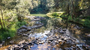 Light and shadows on shallow water flowing over rocks in a creek in the Australian bush