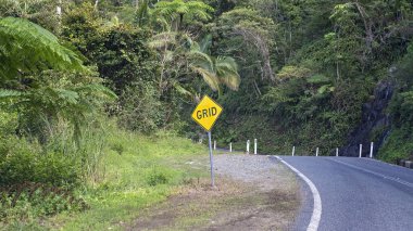 Dağın yukarısındaki kıvrımlı bir yol üzerinde şelalesi olan ulusal bir parka giden bir işaret.