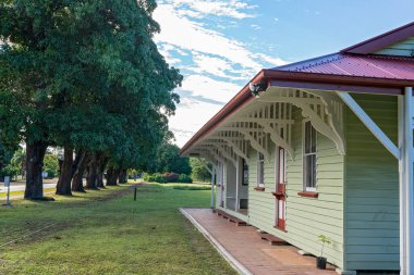 Mackay, Queensland, Avustralya - Haziran 2021: Kullanılmayan eski bir kereste tren istasyonu, önünde sıra sıra mango ağaçları olan bir köy kasabasında bir kır evi zanaat atölyesine dönüştü
