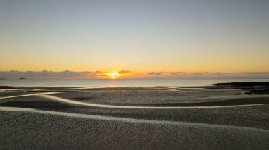 Cape Palmerston Avustralya sahilinde alçak gelgitte güneşin doğuşu.
