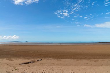 Deniz burnu - güzel düz bir sahil, alçak gelgitte sıcak kum, mavi deniz ve bulutlu gökyüzü