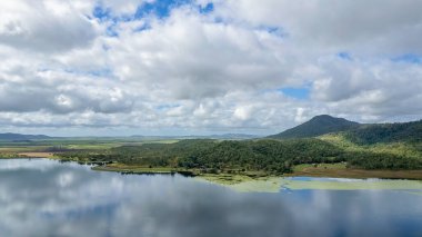 Suya yansıyan bulutlarla dolu bir barajın ayna pürüzsüz yüzeyi. Kinchant Barajı, Queensland, Avustralya.