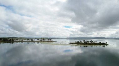 Fırtınalı bulutlu bir gökyüzü Kinchant Barajı, Queensland, Avustralya 'daki durgun suya yansıyor..