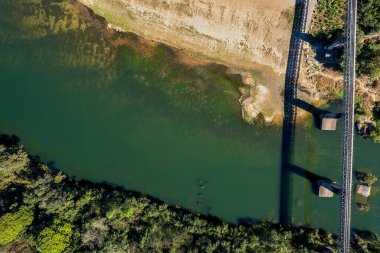 Havadan bakıldığında bir derenin kıyısındaki sahile demiryolu köprüsü ile bakıyor.