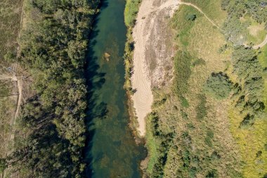 An aerial landscape of the patterns in the sand, the texture in the water, and the trees of a country creek