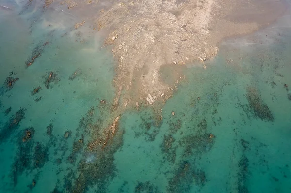 Dalgalar alçaldığında okyanus manzarası soyut şekillerde kumsalları ve deniz suyunu gösteriyor. Cape Hillsborough, Queensland, Avustralya
