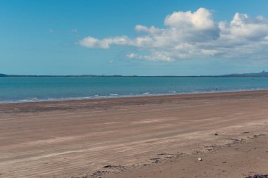 Uzakta bir balıkçının olduğu sahnenin sinematik renk tonları ve kumların üzerinden gelen gelgit.