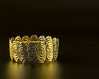 Siyah arka planda altın bir bilezik.