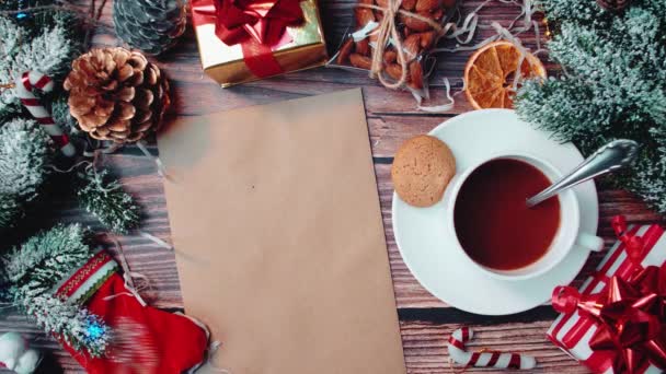 Frohe Weihnachten Konzept mit Tannenzweigen und einer Tasse Kaffee, Dekoration und Hand legt leeres Papier auf den Tisch. — Stockvideo