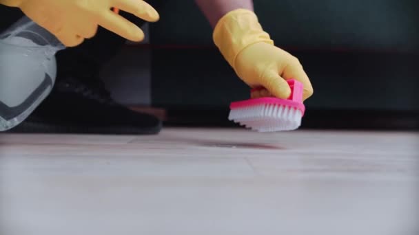 Um trabalhador limpa o chão com detergente usando uma escova rosa e luvas de proteção amarelas. Close-up. — Vídeo de Stock