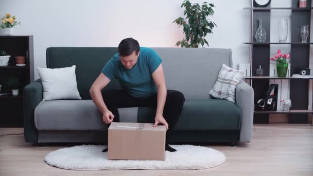 O homem abre o pacote e está muito feliz com o que está nele. — Vídeo de Stock