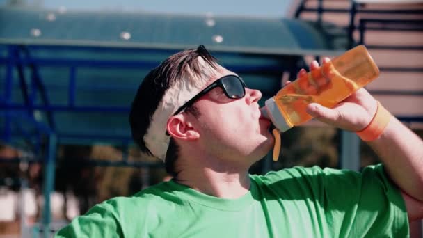 Atleta sediento en el patio bebe agua después del entrenamiento — Vídeos de Stock