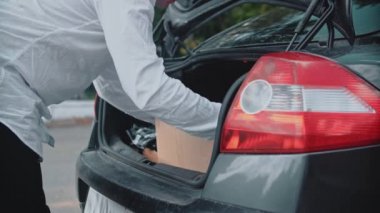 Adamın biri paketleri boşaltır, bir arabanın bagajından karton kutuları alır. Kargo teslimat servisi karantina sırasında. Gönüllü iş.