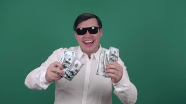 Un homme joyeux portant des lunettes de soleil sourit et tient des billets d'un dollar. Mouvement lent — Video