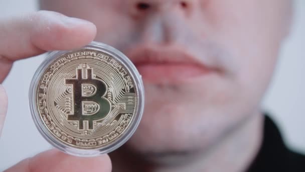 Un uomo tiene un bitcoin in mano. Bitcoin sullo schermo. Nuovo concetto finanziario. — Video Stock