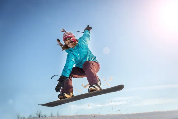 Jovem mulher no snowboard jumping — Fotografia de Stock