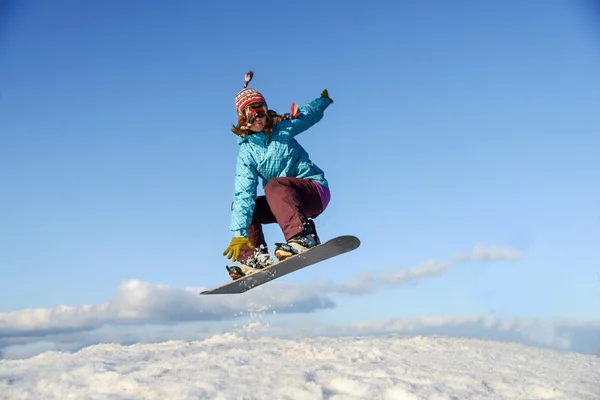 Jovem mulher no snowboard jumping — Fotografia de Stock