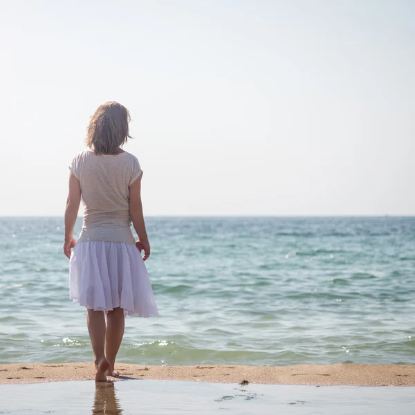 Flicka står vid stranden — Stockfoto