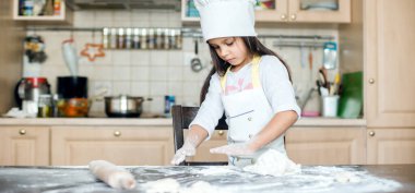 Küçük kız mutfakta yemek pişiriyor..