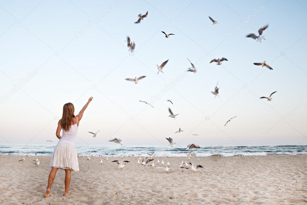 Woman at Beach are Feeding Seagulls