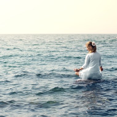 Woman meditating at the sea clipart