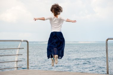 Genç bir kadın plajda atlıyor.