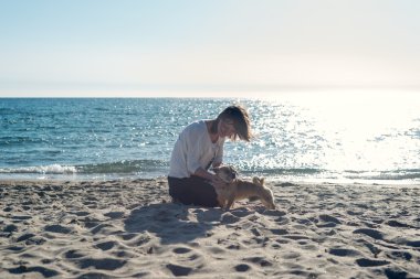 Kumsalda köpeğiyle oynayan bir kadın..