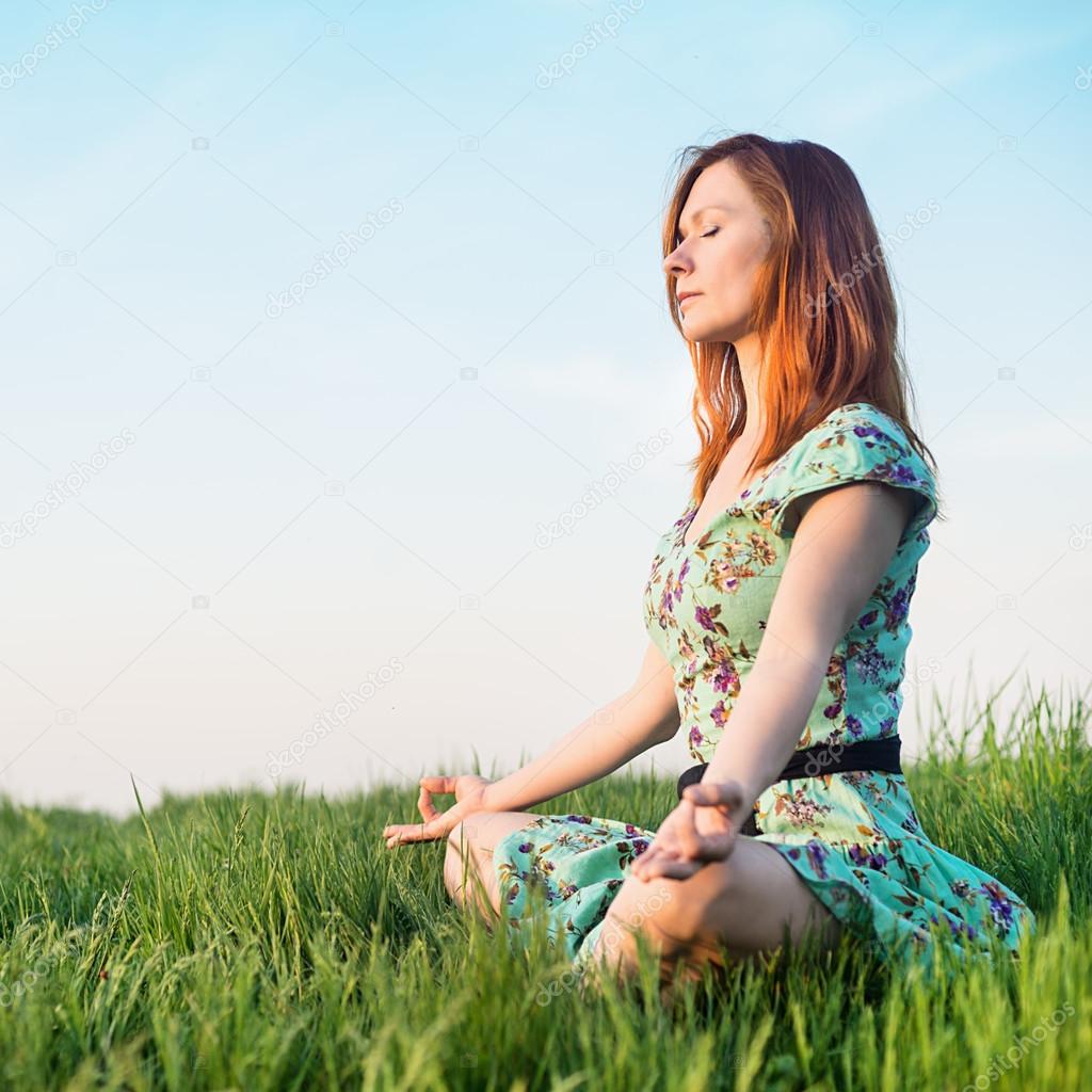 Pretty woman meditate in the park