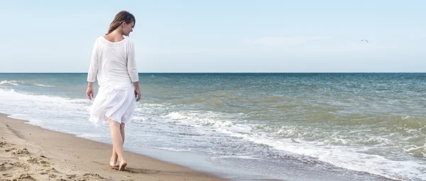 Mujer en vestido de verano de pie sobre un mar — Foto de Stock