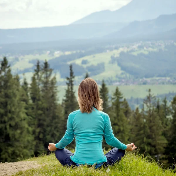 Kvinnan meditera på bergen Stockbild