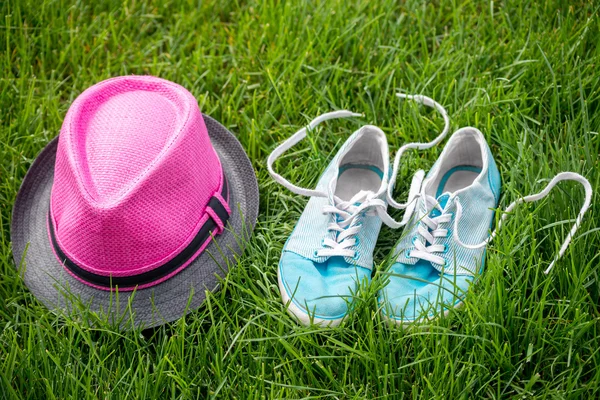 Zapatillas de deporte y sombrero sobre hierba —  Fotos de Stock