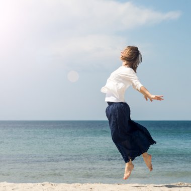 Genç bir kadın plajda atlıyor.