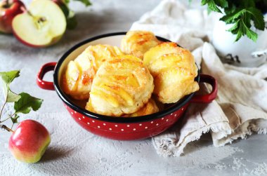 Gri arka planda bir kasede karamelli elmalı krep.