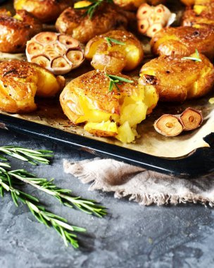 Kırık patatesler, arka planda gri bir tabakta biberiyeyle pişirilmiş.