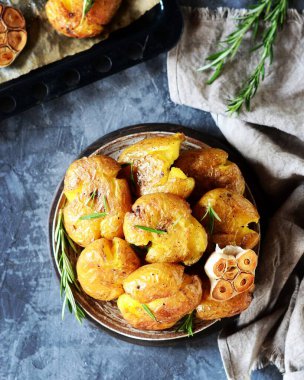 Kırık patatesler, arka planda gri bir tabakta biberiyeyle pişirilmiş.