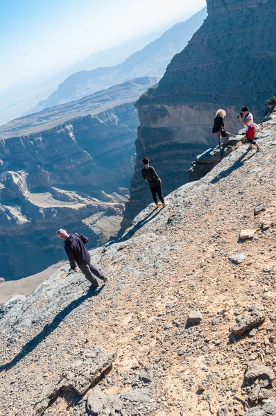 Tourists posing for photos standing on the edge of Canyon, Oman — Stock Photo, Image