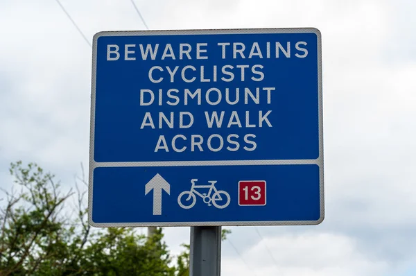 Passagem ferroviária sinal de aviso cuidado trens ciclistas desmontar e andar através Imagens Royalty-Free