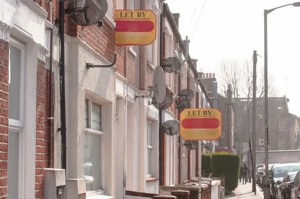 Estate agent "let by" signs line the road in a suburb of London — Stock Photo, Image