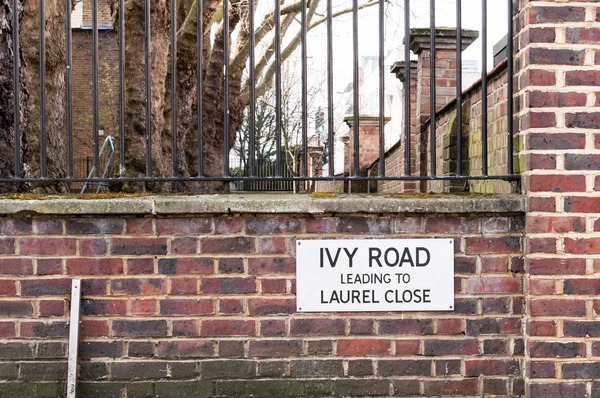 Ivy Road johtaa Laurel Close Street Merkki vastaan tiiliseinä — kuvapankkivalokuva